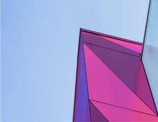 A folded magenta and violet flank of the Eebox Building meeting pale blue sky at a knife-sharp edge.