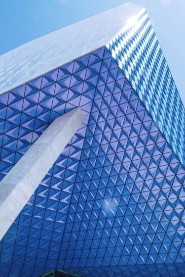 Looking up the faceted blue glass ridge of Project Paramour against a clear sky.