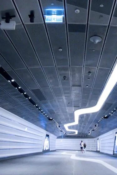 The white concourse of Seraph Station, lit by a single ribbon of neon across its dark ceiling.
