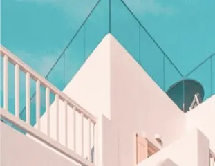 Stacked white terraces and a slim glass balustrade set against a bright turquoise sky.